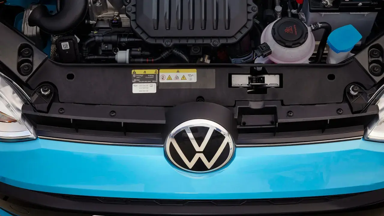 Motorutrymmet på en blå Volkswagen. En etikett visar information om olja och kylvätska, vilket kan vara relevant vid ett volkswagen gasbil problem.