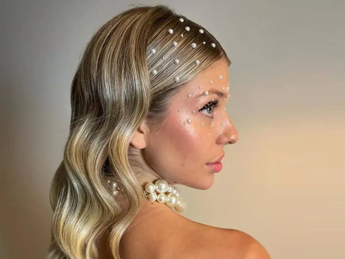 Peinados para salir de fiesta: melena rubia ondulada adornada con perlas en el cabello y rostro, look deslumbrante.