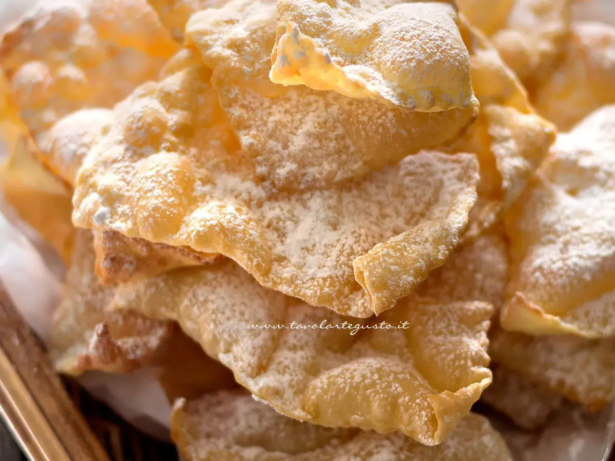 Chiacchiere croccanti, una deliziosa chiacchiere ricetta della nonna, cosparse di zucchero a velo.