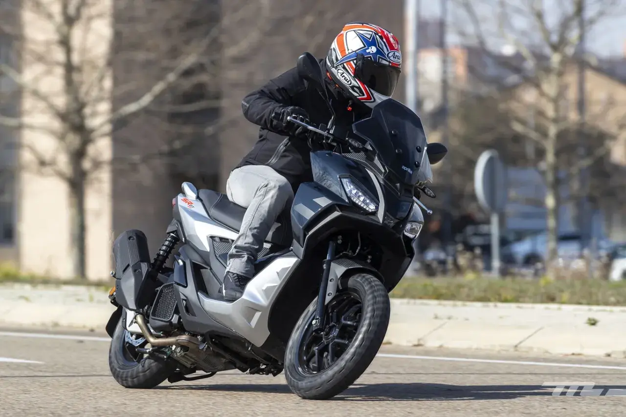 Motorista con casco a bordo de una Aprilia SR GT 125, lista para alcanzar su velocidad máxima en la carretera.