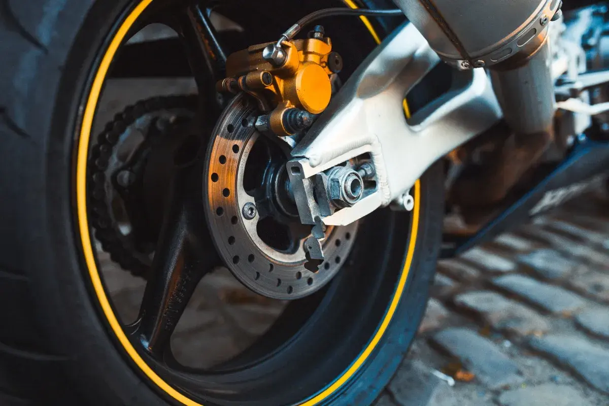 Motorradbremse mit gelbem Bremssattel. Zeit für einen neuen Bremsbelag wechseln, um sicher unterwegs zu sein.