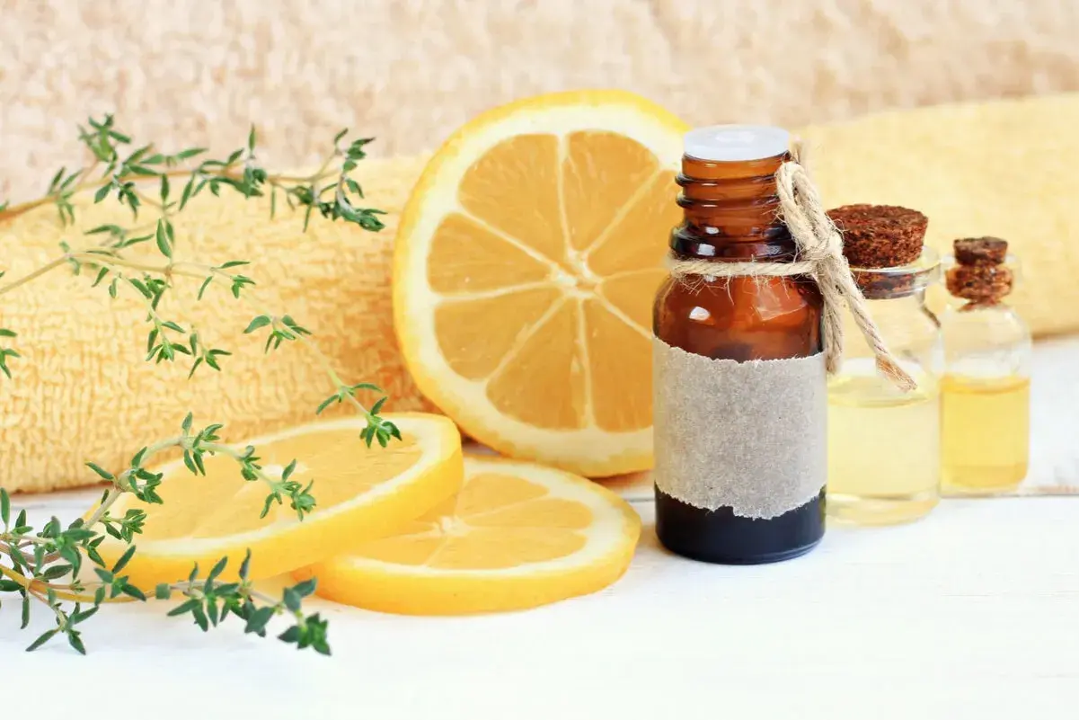 Aceite esencial de limón, con rodajas de limón y ramitas de tomillo. El limoneno es un componente clave.