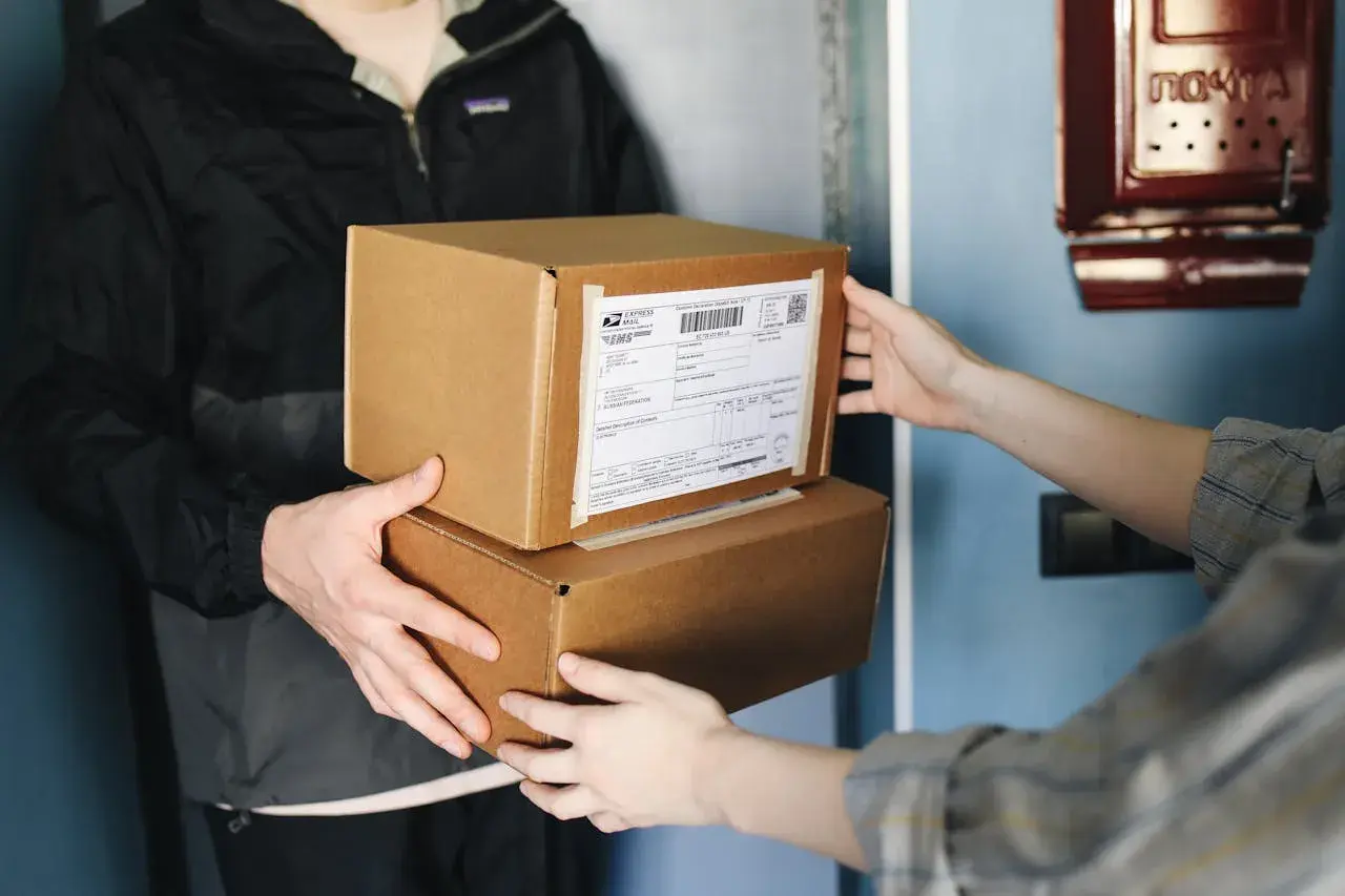 Dwie osoby przekazują sobie paczki. Na jednej z nich widoczna jest etykieta z kodem kreskowym. Ile cyfr ma kod nadania InPost?
