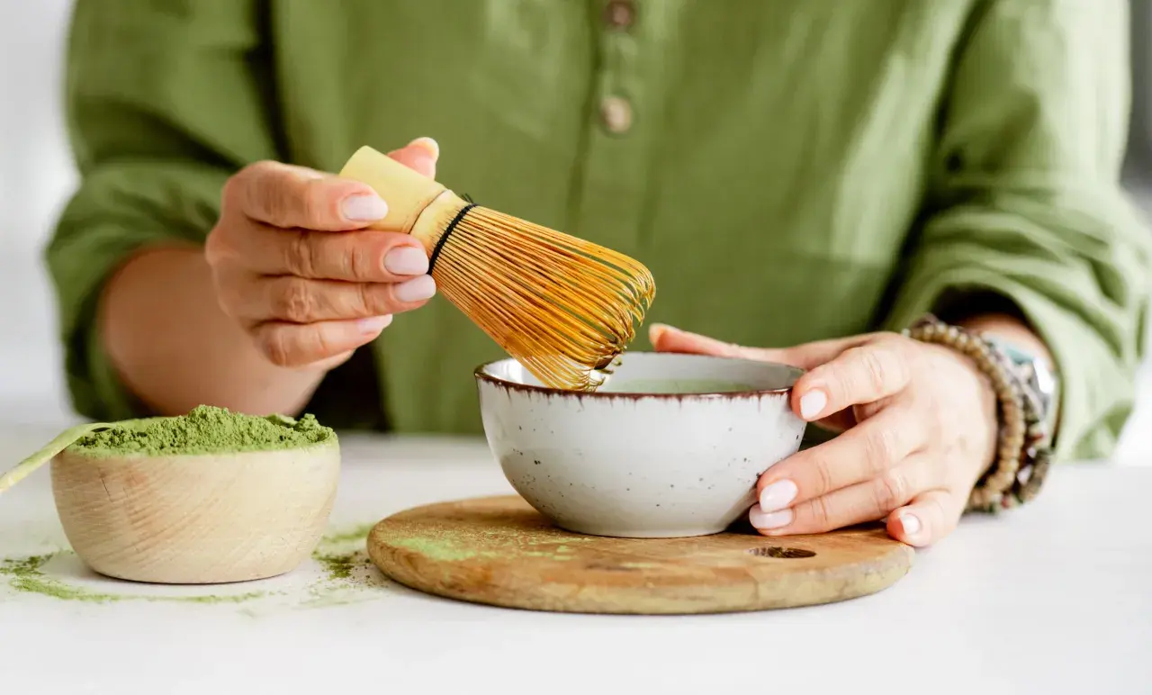 Przygotowanie najlepszej zielonej herbaty matcha. W drewnianej miseczce proszek, w ceramicznej miseczce napar, ubijany bambusowym miotełką.