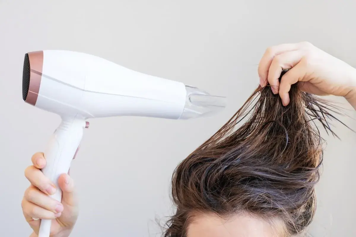 Secando el pelo mojado con un secador para dar volumen al pelo fino.