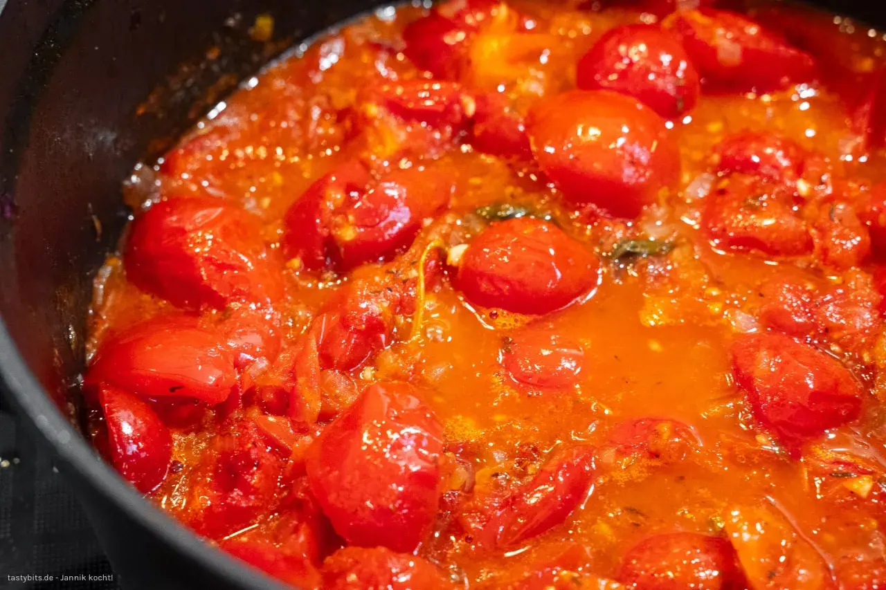 Frische, glänzende Tomaten köcheln in einer Pfanne zu einer aromatischen Tomatensauce.