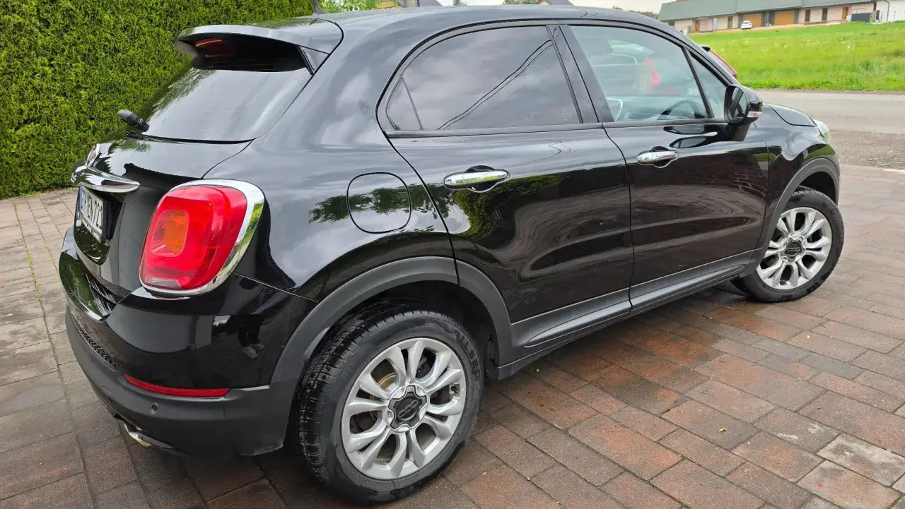 Czarny Fiat 500X widziany z boku, na brukowanym podjeździe.