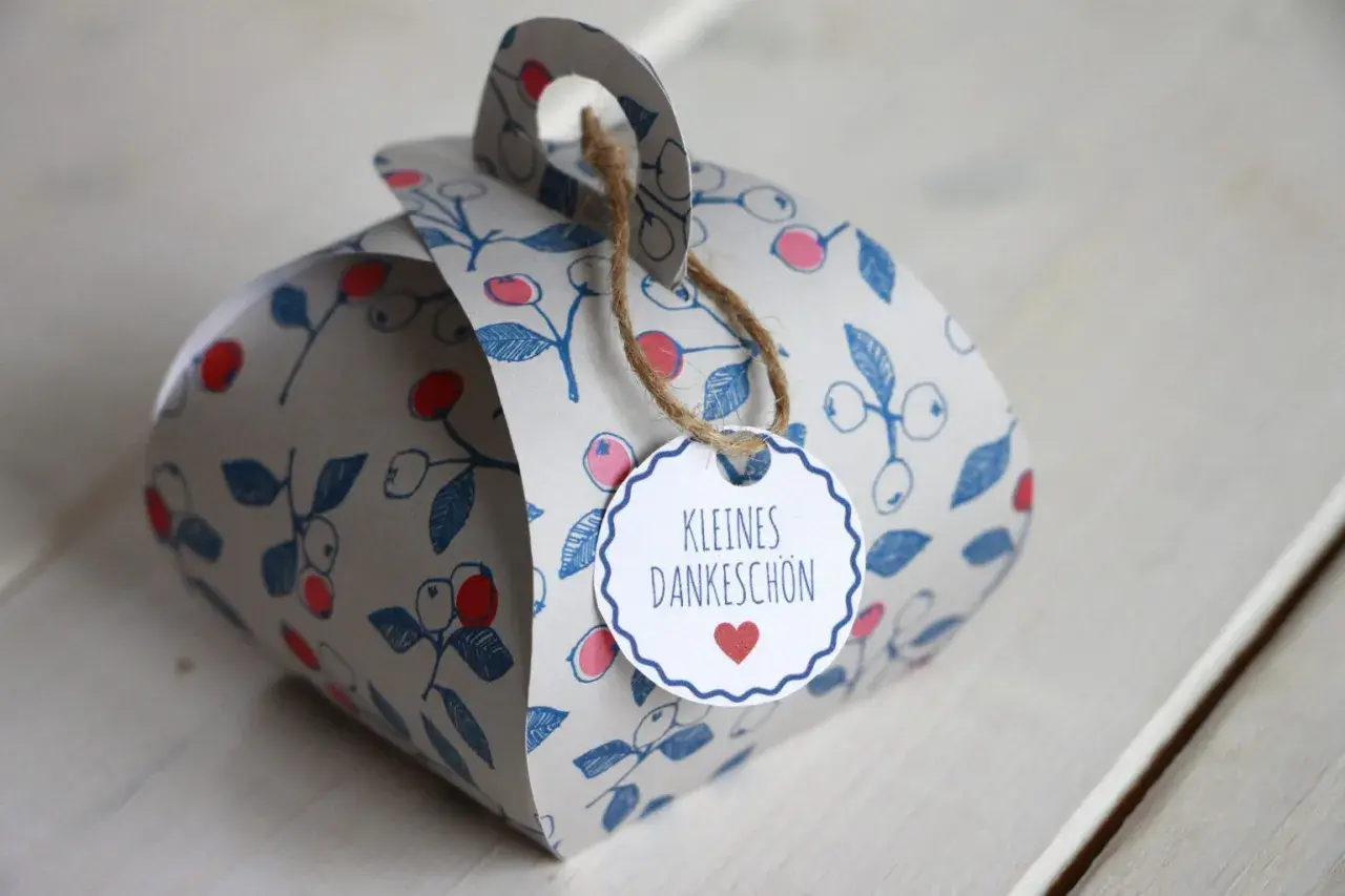 Eine liebevoll gestaltete DIY Geschenkbox mit Beerenmuster und dem Anhänger "Kleines Dankeschön".