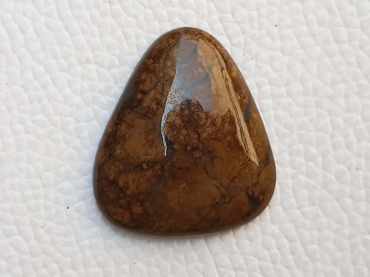 Piedra marrón con vetas oscuras, su significado evoca conexión con la tierra y estabilidad.