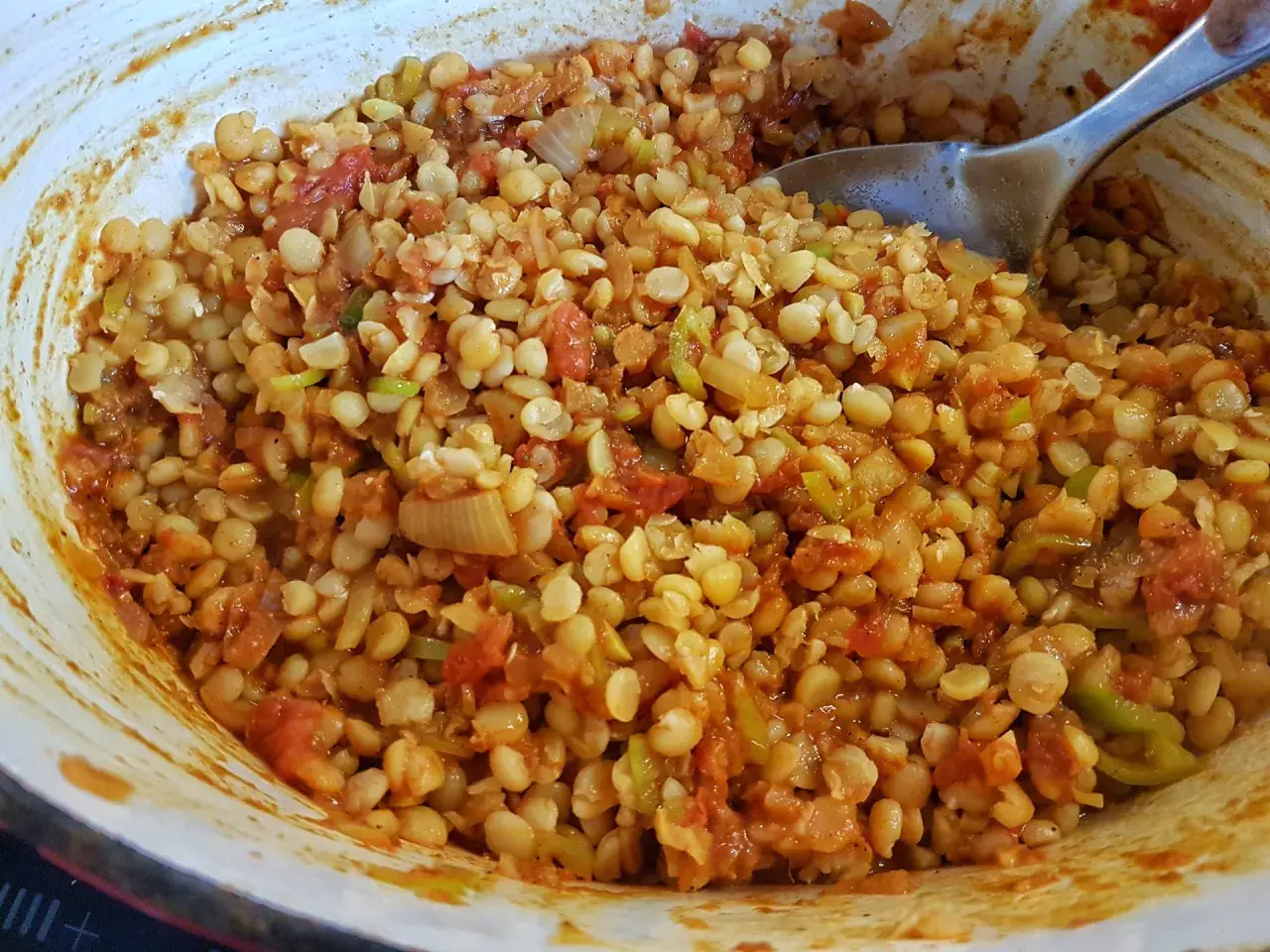 En skål med kryddig chana dal, en indisk linsrätt med tomat och lök, redo att serveras.
