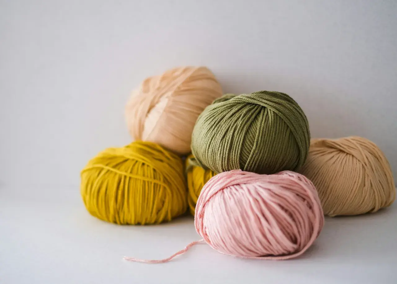 Pelotes de laine aux couleurs pastel, dont une rose pâle, une verte et une jaune. La matière semble être du nylon, parfaite pour des créations durables.