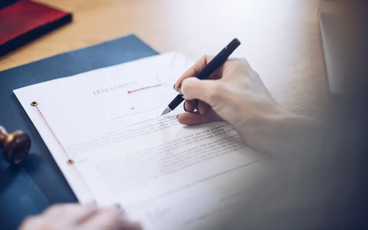 Dłoń pisze piórem na dokumencie testamentu. To ważny testament allograficzny, który określa przyszłość.