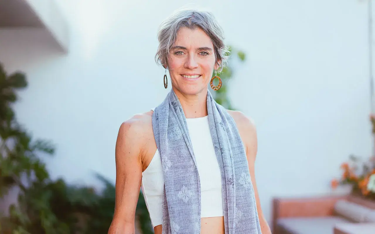 Donna sorridente con sciarpa grigia, un esempio di quanto deve essere lunga una sciarpa da donna per un look casual e chic.