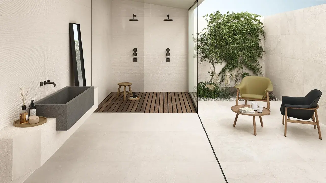 Bagno moderno con vasca in pietra, doccia a filo pavimento e un'area relax esterna. Il tipo di pavimentazione in gres porcellanato chiaro unifica gli spazi.