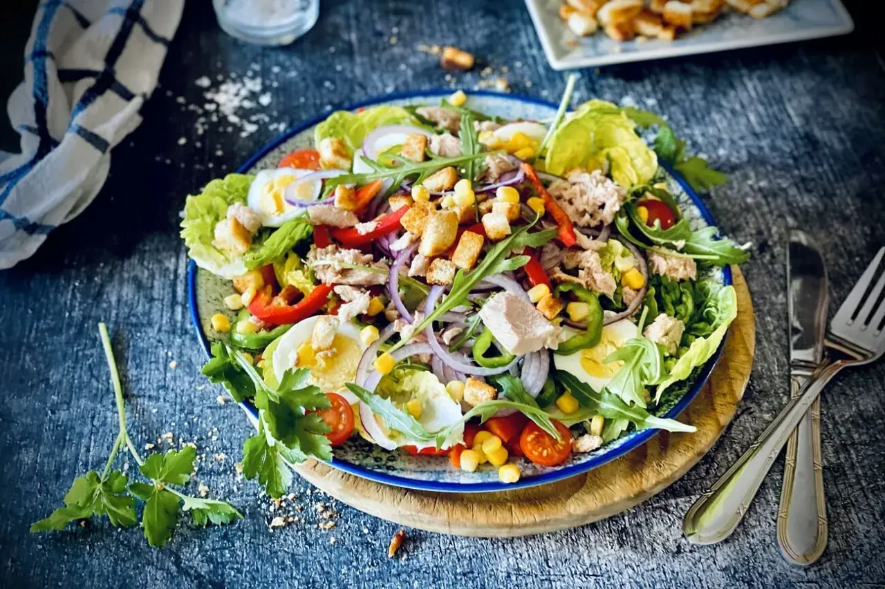 Ein bunter, klassischer Thunfischsalat mit knackigem Salat, Ei, Paprika, Mais, Zwiebeln und Croutons.