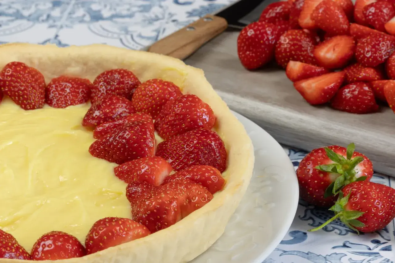 Une délicieuse tarte aux fraises et crème pâtissière, prête à être dégustée. Des fraises fraîches garnissent généreusement cette pâtisserie.
