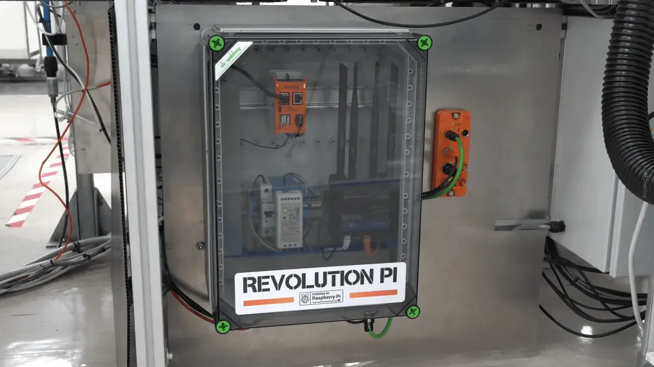 Wewnątrz przezroczystej obudowy widać system sterowania z napisem "REVOLUTION PI POWERED BY Raspberry Pi". To pokazuje, że raspberry co to za urządzenie, które zasila ten przemysłowy komputer.