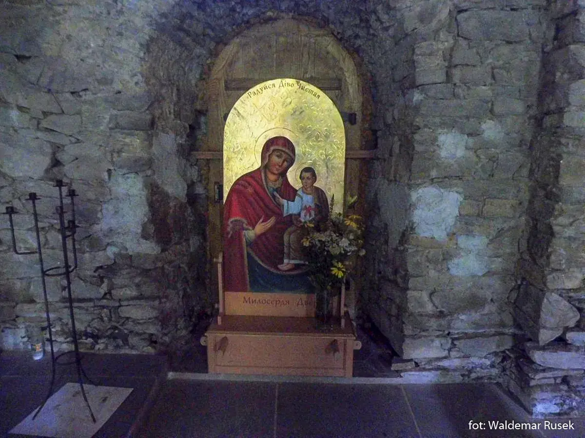 Ikona Matki Boskiej z Dzieciątkiem w kamiennej niszy cerkwi w Łopience. Obok świecznik.