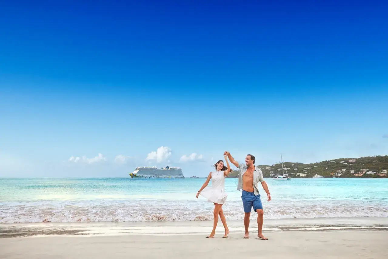 Ett lyckligt par dansar på stranden i San Juan, med ett kryssningsfartyg i bakgrunden.