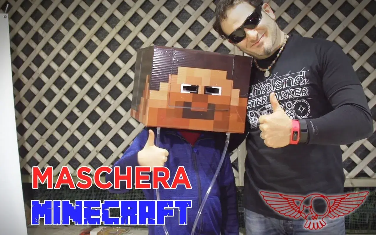 Un bambino indossa una maschera fai da te di Minecraft. Un uomo sorride e fa il pollice in su.