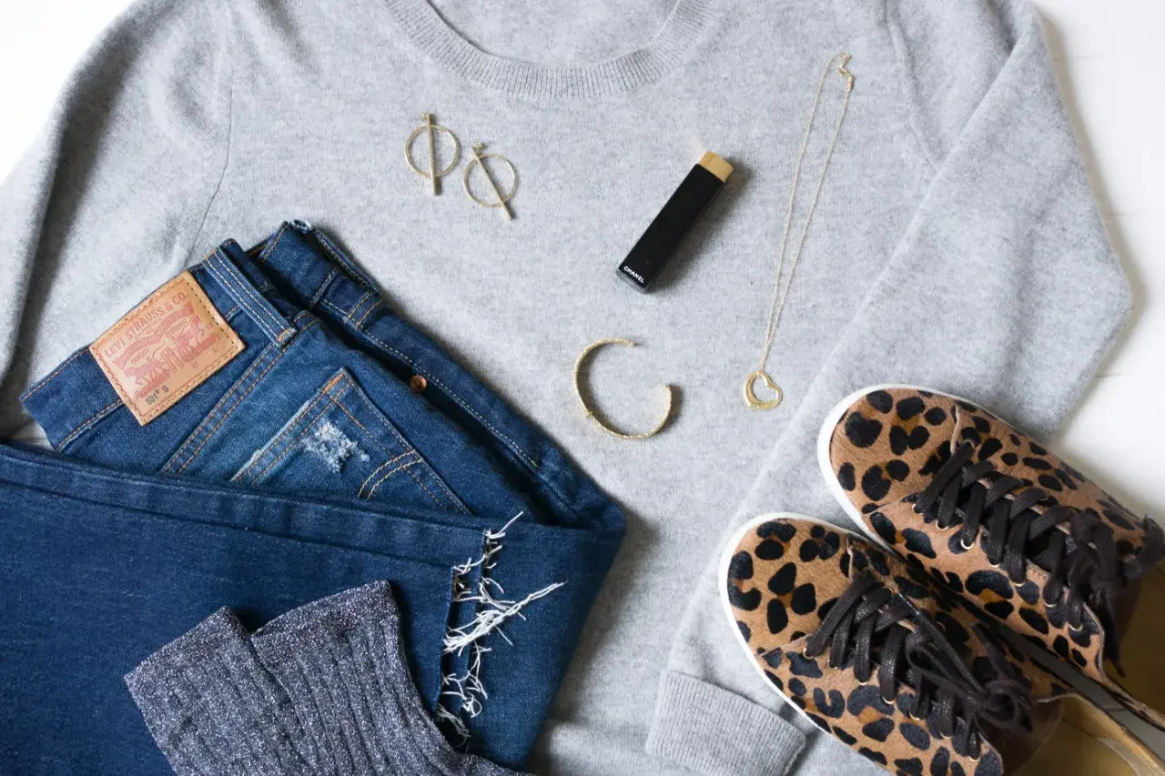 Un pull gris, un jean Levi's, des chaussettes scintillantes, des baskets léopard, un collier cœur, des boucles d'oreilles et un rouge à lèvres Chanel pour s' habiller simplement.