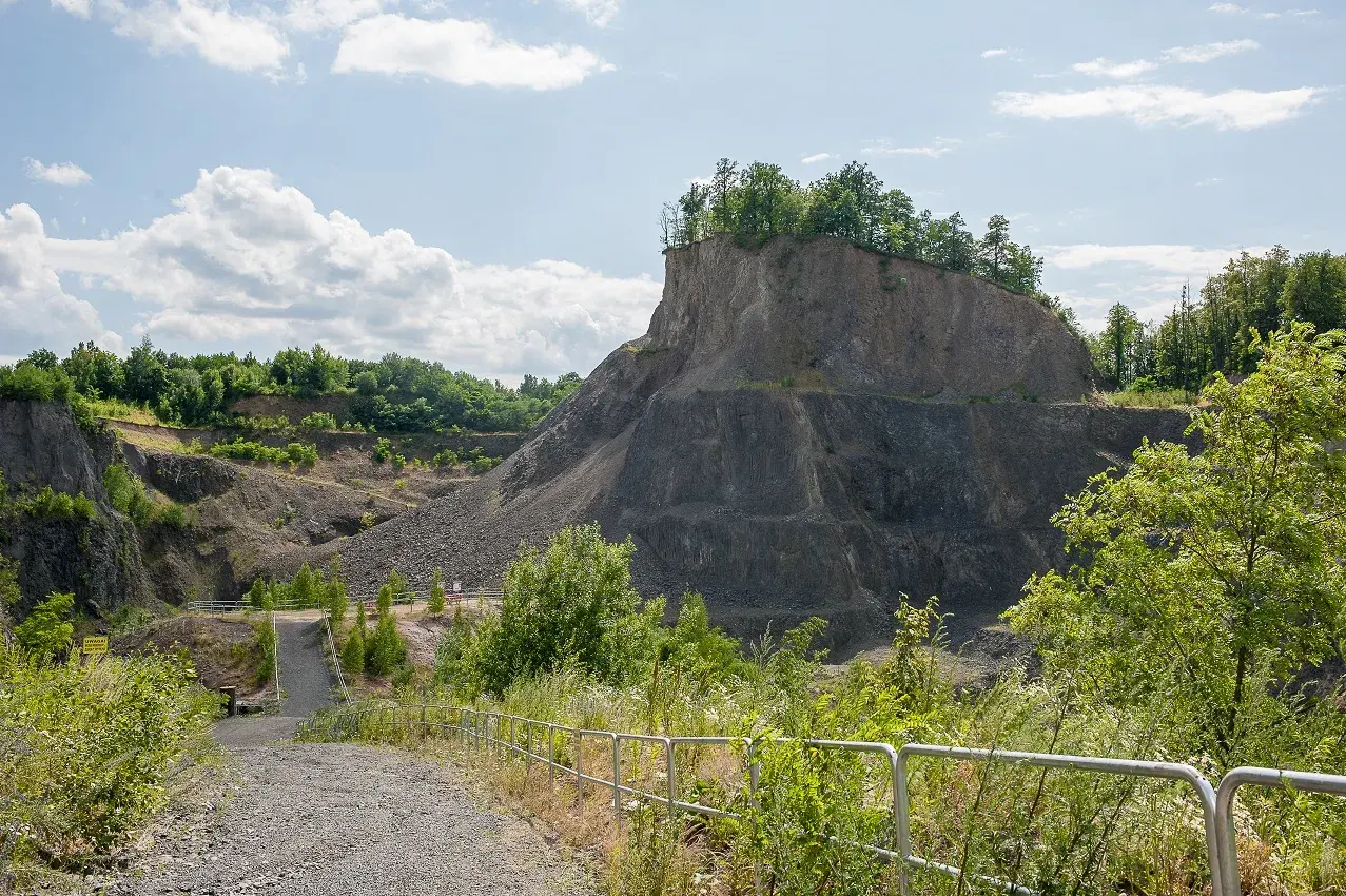 Kamieniołom przypomina wilczą górę, z której wyrasta bujna zieleń. Ścieżka prowadzi w głąb skalistego krajobrazu.