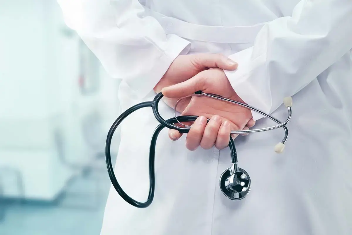 Mani di un medico con stetoscopio dietro la schiena, forse riflettendo su dimissioni dirigente medico e ferie non godute.