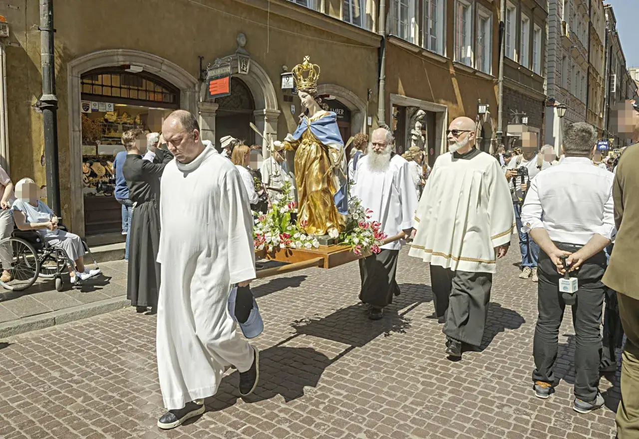 Procesja z figurą Matki Boskiej. Czy w Boże Ciało trzeba iść do kościoła? Wierni niosą figurę ulicą, niektórzy w strojach duchownych.