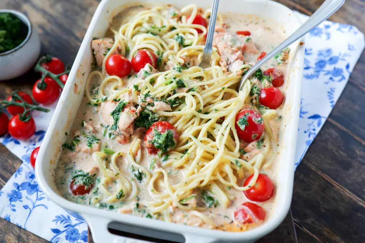 Cremige Lachs Spinat Pasta mit Kirschtomaten in einer Auflaufform, bereit zum Servieren.
