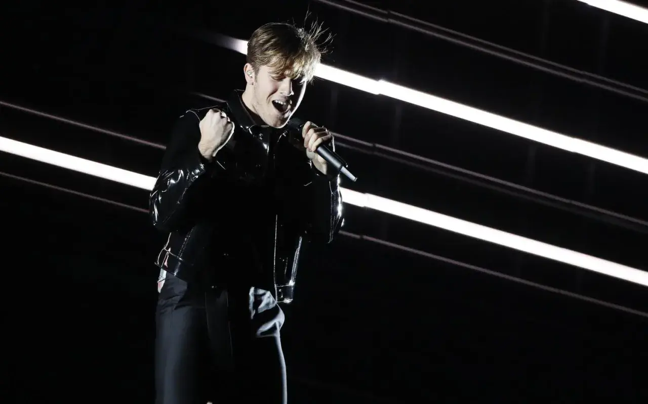 Benjamin Ingrosso levererar på scenen under Eurovision. Han sjunger passionerat med mikrofonen i handen, klädd i en glänsande svart jacka.