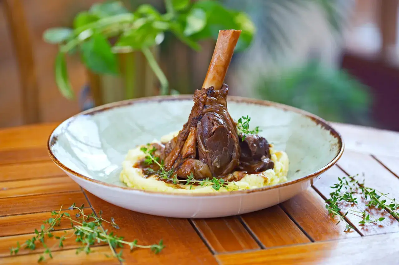 Une souris d'agneau braisée, servie sur une purée onctueuse et garnie de thym frais. Un plat savoureux et réconfortant.