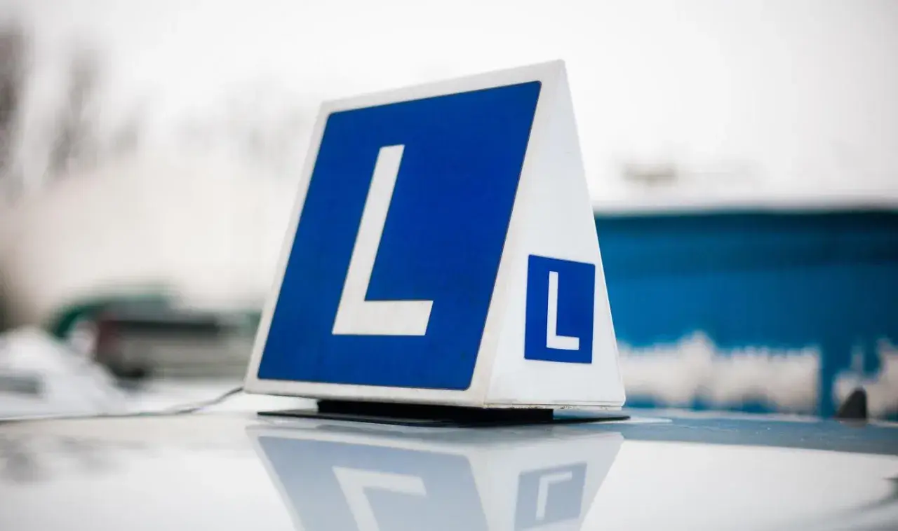 Tablica z literą "L" na dachu samochodu. Zastanawiasz się, ile kosztuje prawo jazdy?