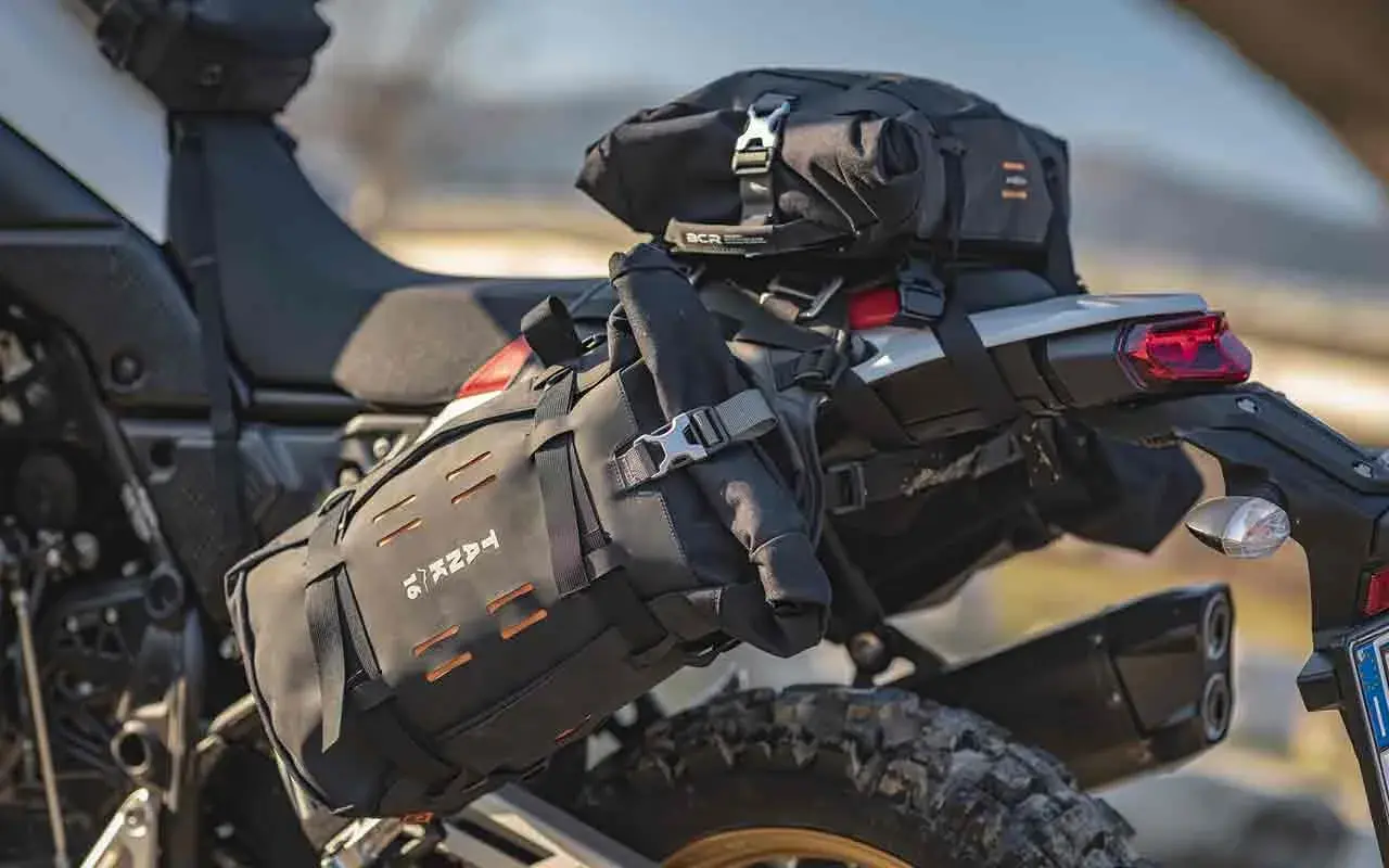 Borsa roll bag nera fissata sul retro di una moto da enduro, pronta per un'avventura.