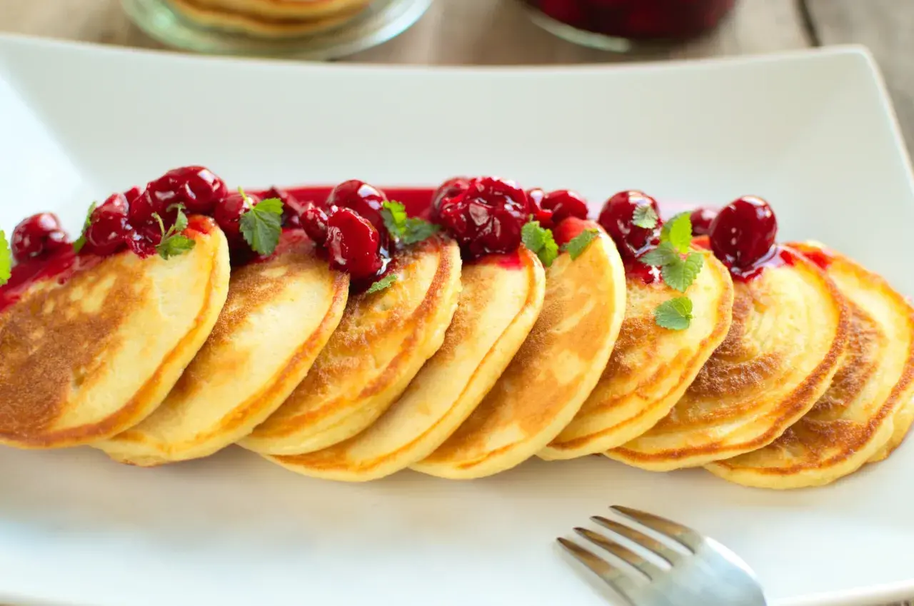 Złociste placuszki, idealne na śniadanie, polane wiśniowym sosem i udekorowane listkami mięty. Pyszny przepis na pancake!