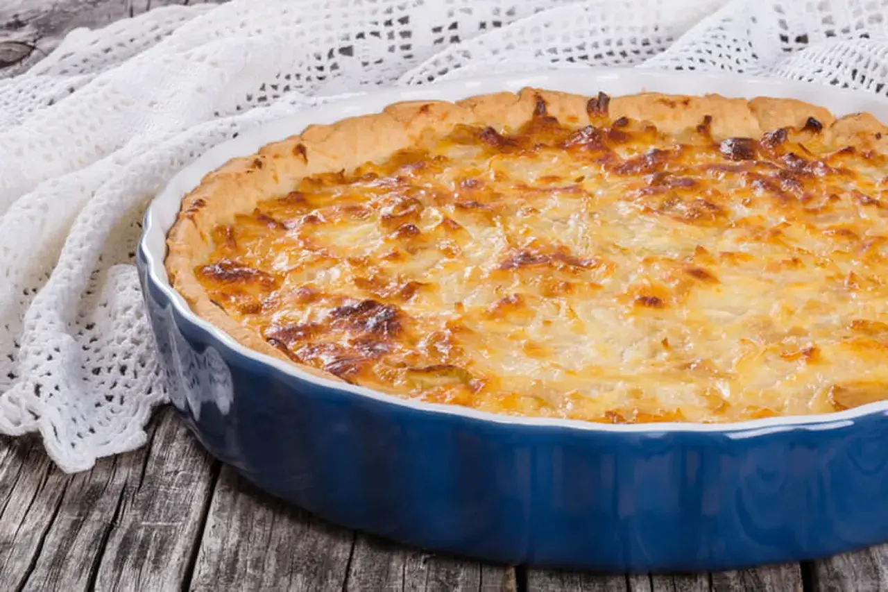Quiche lorraine dorée dans un plat bleu. Le temps de cuisson et la température parfaits pour un délice croustillant.