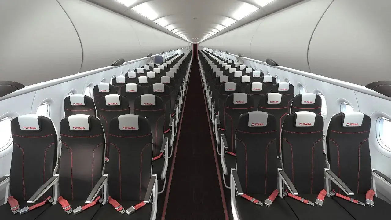 Wnętrze samolotu linii lotniczych Electra Airways. Rzędy czarnych foteli z czerwonymi przeszyciami i białymi zagłówkami z logo ITAKA.