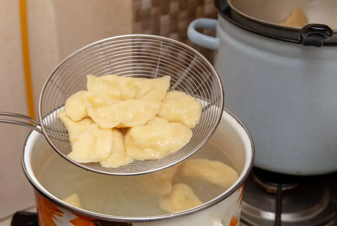 Gotowanie pierogów: cedzak z pierogami nad garnkiem z wrzącą wodą. Tak, pierogi wrzuca się do gotującej wody.