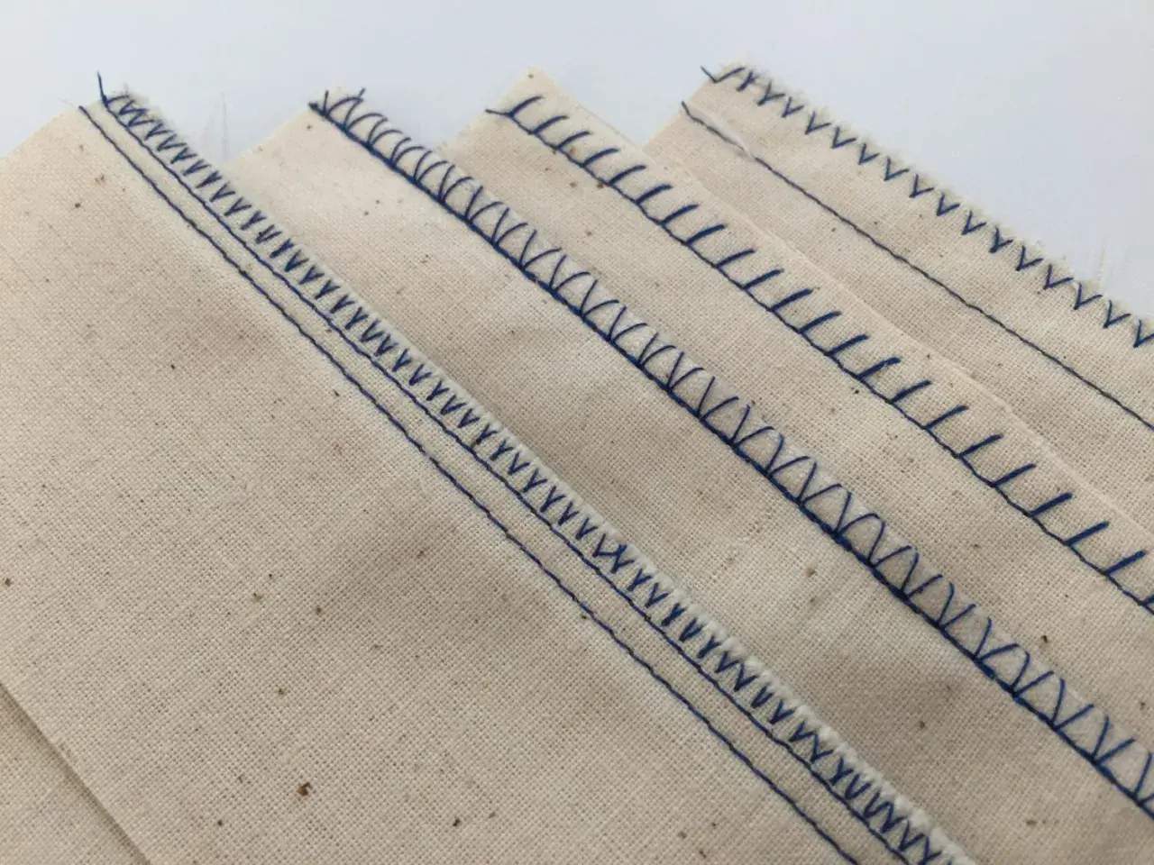 Close-up of beige fabric with neat, blue serger stitches. This is what a serger does: finishes edges beautifully.