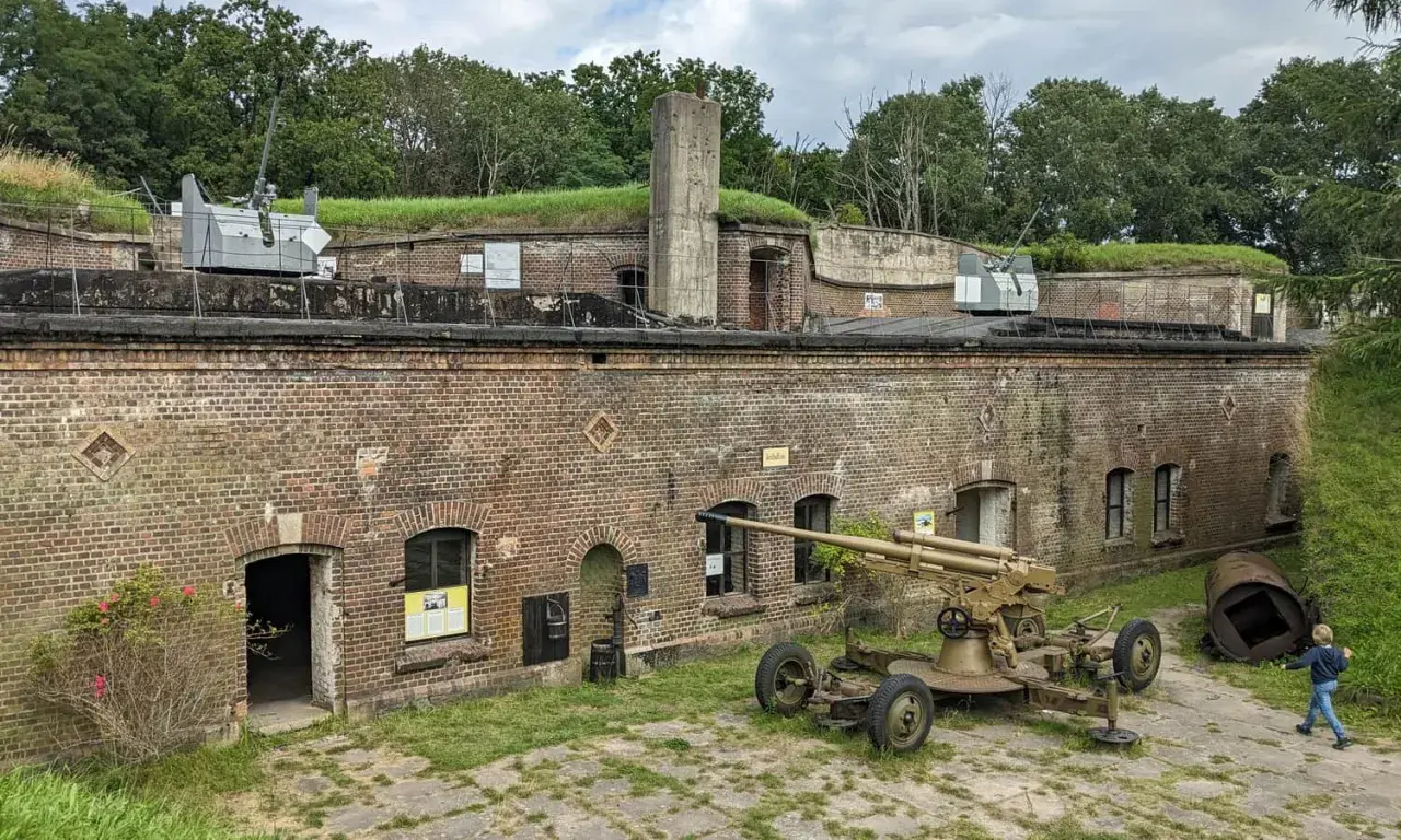 Fort Zachodni z działami na murach i ziemi. Dziecko biega obok zabytkowej broni.