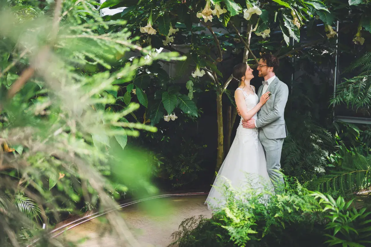Brautpaar im Grünen, umgeben von üppiger Vegetation. Tolle Spalier Hochzeit Ideen für eine romantische Zeremonie.