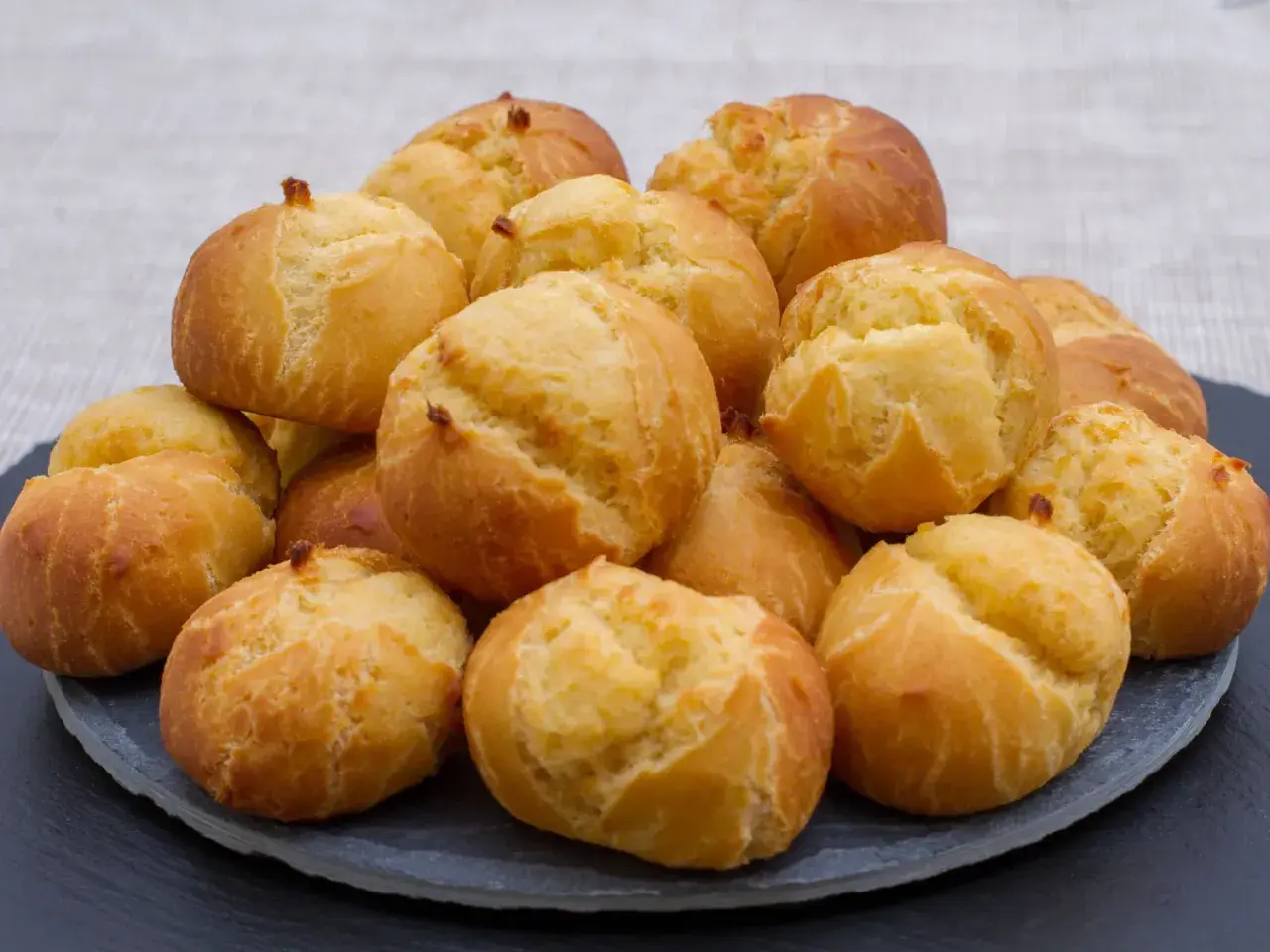 Pile de gougères dorées et gonflées, parfaites pour apprendre comment faire gonfler des gougères.