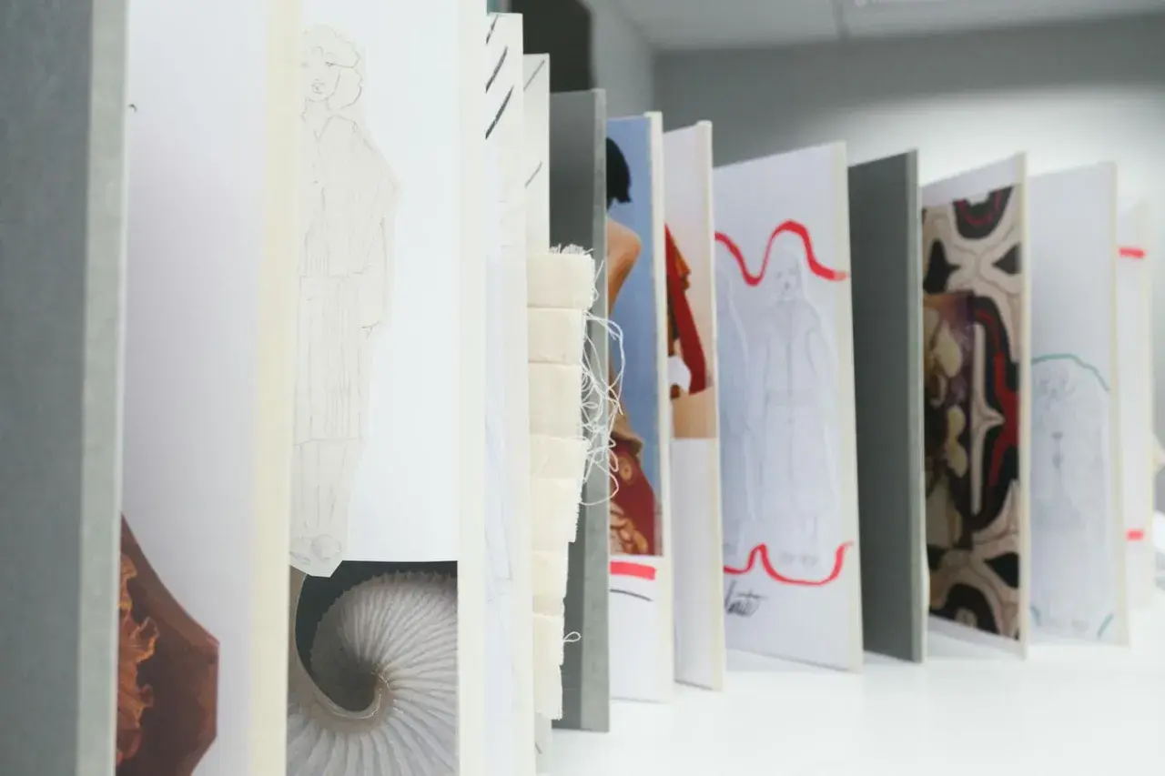 Un acheteur textile parcourt des croquis de mode, des échantillons de tissu et des motifs, imaginant de futures collections.