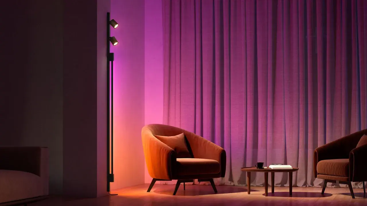 Sofá naranja y cortinas moradas iluminados por luces domoticas, creando un ambiente acogedor.