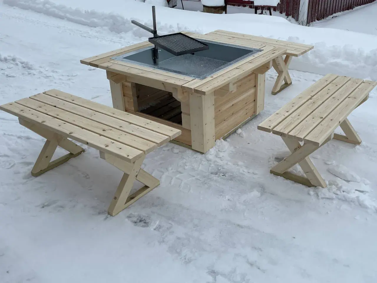 En ny grillplats i trä med bänkar, perfekt för grillplats inspiration i vinterlandskapet.