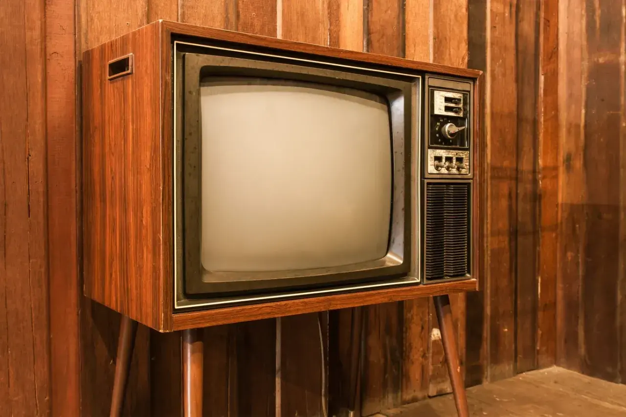 Stary telewizor z drewnianą obudową i ekranem kineskopowym. Ciekawe, w którym roku powstał pierwszy telewizor, bo ten wygląda na prawdziwy antyk.