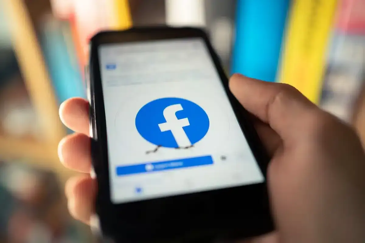 Dłoń trzyma smartfon z logo Facebooka. Chcesz wiedzieć, jak usunąć fb ale zostawić messengera?