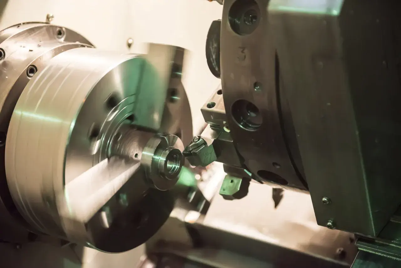Precyzyjne toczenie aluminium na obrabiarce CNC. Metalowy element obraca się, a narzędzie precyzyjnie nadaje mu kształt.