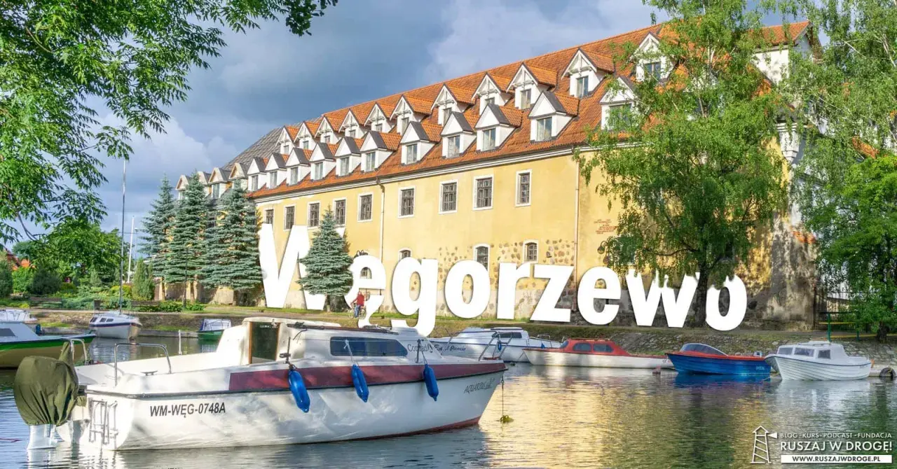 Węgorzewo: malowniczy widok na port z łodziami i zabytkową kamienicą. Idealne miejsce na rodzinne wycieczki, oferujące wiele atrakcji dla dzieci.