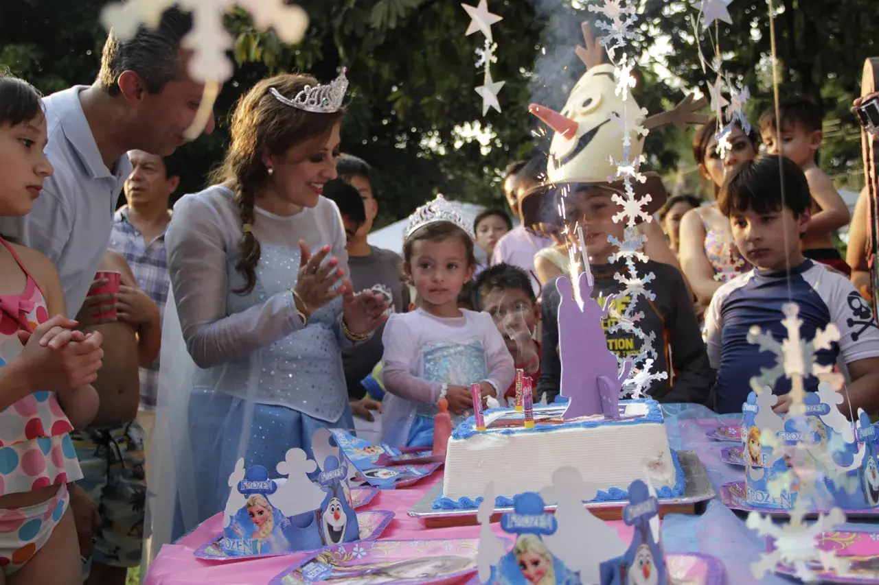 Celebración de cumpleaños en aula infantil con pastel de Frozen y niños emocionados.