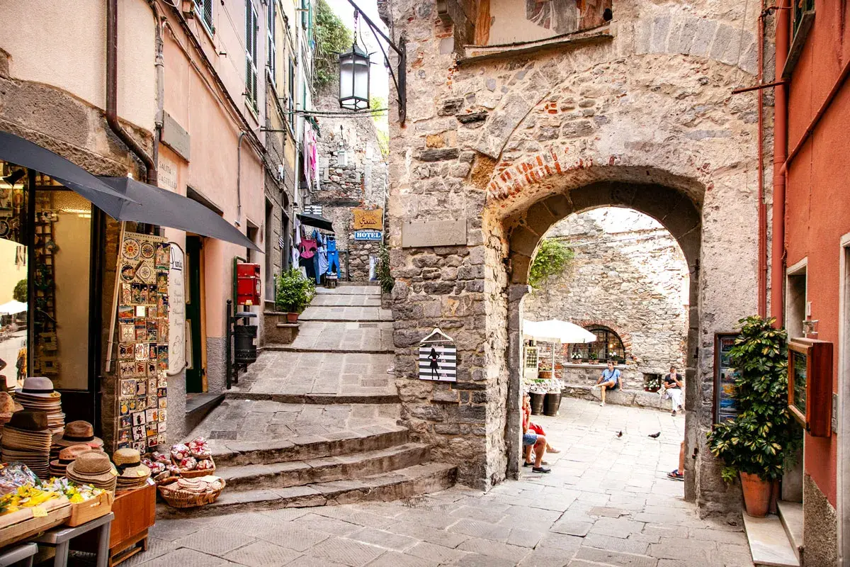 Un vicolo pittoresco nel portovenere centro storico, con negozietti, scalinate in pietra e un arco antico.